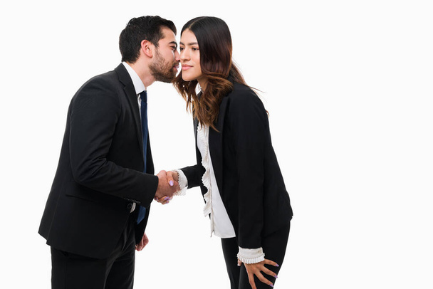 Don't tell anyone my secret. Successful accountant whispering to a female lawyer while shaking hands  - 写真・画像