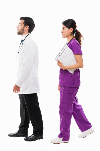 Widok z boku lekarza i pielęgniarki spacerujących razem w szpitalu. Pełna długość personelu medycznego pracującego w szpitalu - Zdjęcie, obraz
