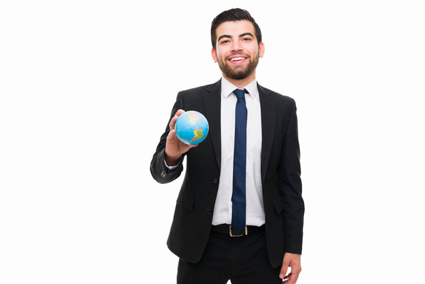 Attractive happy man working as a lawyer around the world while holding a globe in front a white background - Valokuva, kuva