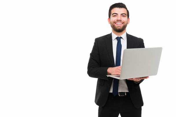 Successful young lawyer. Attractive businessman working on his laptop and smiling to the camera next to copy space - Photo, Image