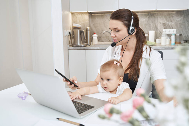 Female clicking on cellphone while working at home with baby - Φωτογραφία, εικόνα