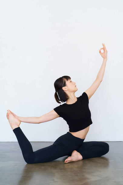 Young woman doing yoga (dove pose)  - Photo, Image