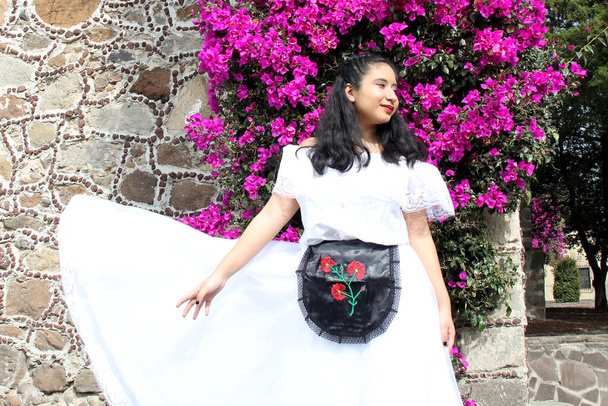 Junge Frau trägt ein weißes Veracruz-Kleid mit schwarzer Schürze, stolz auf ihre mexikanische Kultur und Tradition, bereit zum Tanzen - Foto, Bild
