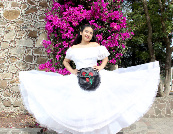 Junge Frau trägt ein weißes Veracruz-Kleid mit schwarzer Schürze, stolz auf ihre mexikanische Kultur und Tradition, bereit zum Tanzen - Foto, Bild