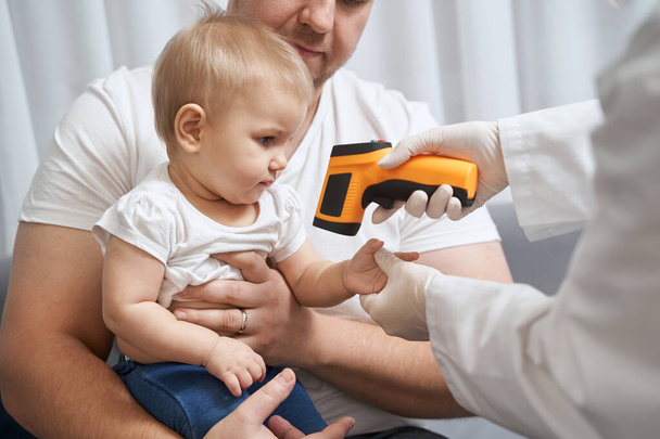 Doctor checking baby temperature with infrared thermometer - Foto, Imagen