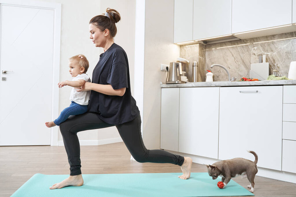 Woman doing side lunge with child in hands - Foto, Imagem