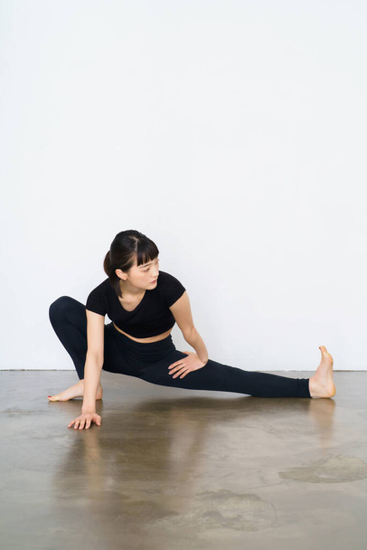 Женщина делает гибкие упражнения (сгибание и растяжение одной ноги)  - Фото, изображение