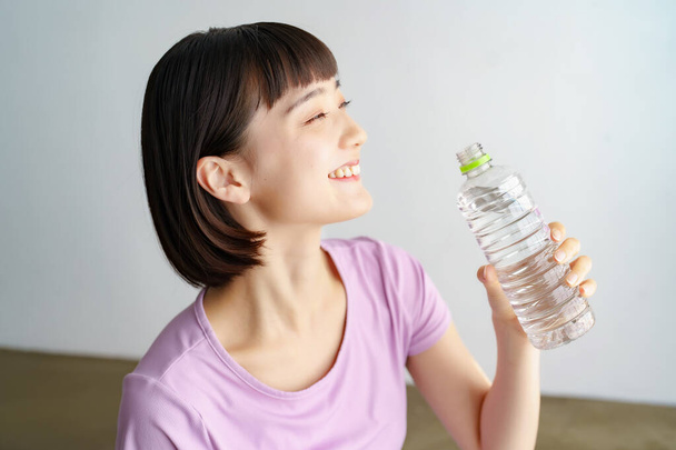 Asian young woman hydrating in sportswear indoors - Photo, Image