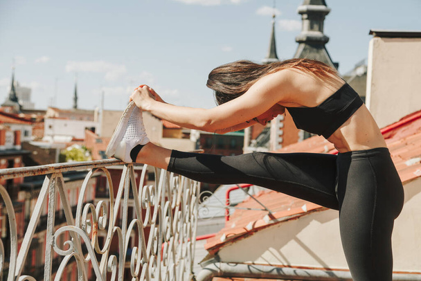 Sportwoman stretching on a rooftop. Healthcare lifestyle concept. - Foto, afbeelding