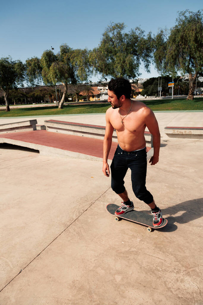 Mann fährt Skateboard im städtischen Straßenskatepark. Lässiger Typ in kurzen Hosen und T-Shirt. - Foto, Bild