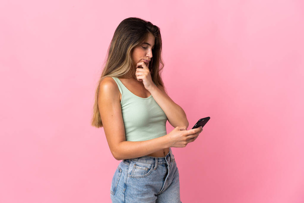 Nuori valkoihoinen nainen eristetty vaaleanpunainen tausta ajattelu ja lähettää viestin - Valokuva, kuva