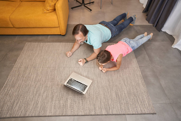 Adulto masculino está fazendo exercícios em casa com adolescente na sala de estar - Foto, Imagem