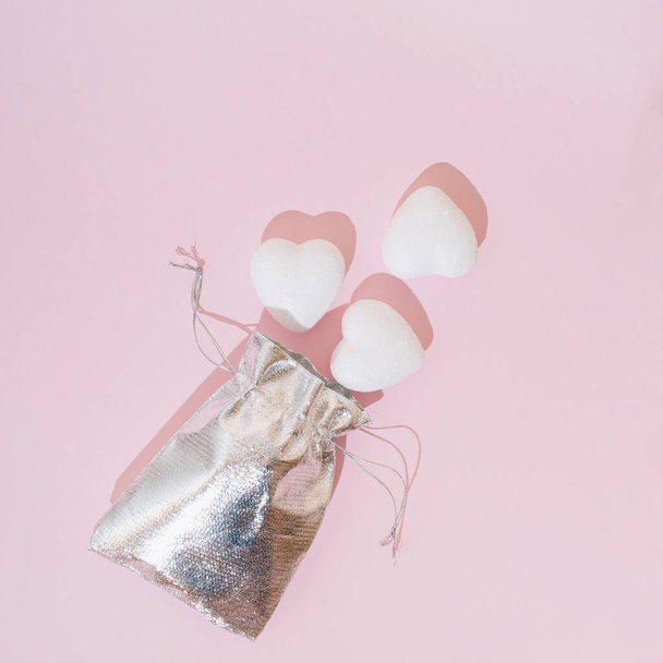 Zilverkleurige tas met hartjes op een roze achtergrond. Valentijnsdag liefde esthetisch concept. - Foto, afbeelding