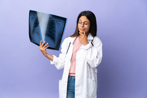 Joven doctora sosteniendo una radiografía teniendo dudas - Foto, imagen