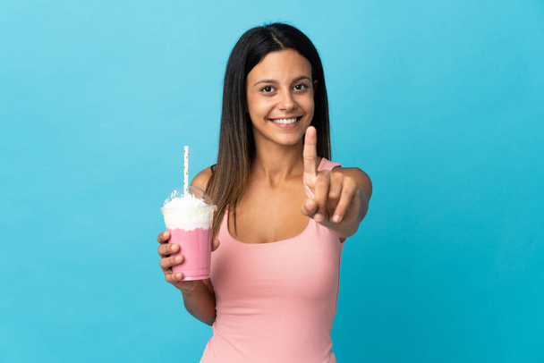 Çilekli milkshake 'li genç kadın parmağını kaldırıyor ve gösteriyor. - Fotoğraf, Görsel