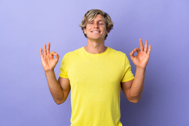 Engelse man over geïsoleerde paarse achtergrond in zen pose - Foto, afbeelding