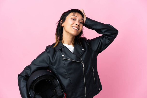 Mladá uruguayská žena drží motocyklovou helmu přes izolované růžové pozadí se smíchem - Fotografie, Obrázek