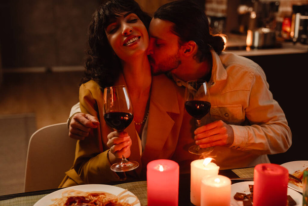 White couple kissing while having romantic dinner at home indoors - Photo, Image