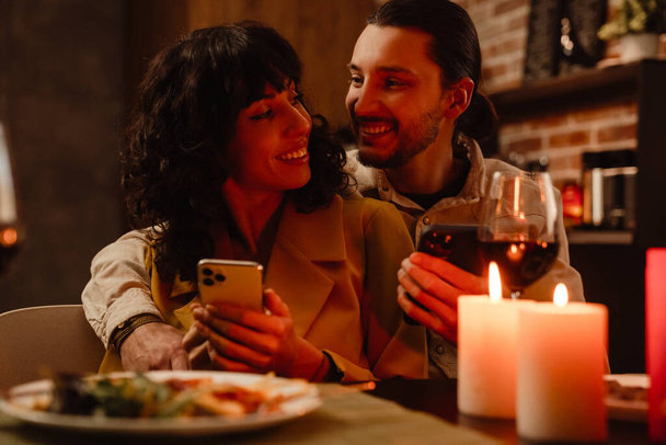White couple using mobile phones during romantic date at home indoors - Foto, imagen