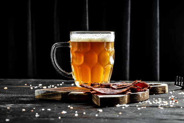 mug of beer and dried fish on dark background, glass with thick foam, . place for text. - Photo, Image