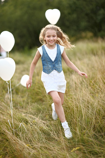 portrait of a little girl in a field with white balloons - Foto, immagini
