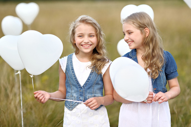 πορτρέτο του ένα μικρά κορίτσια σε ένα πεδίο με λευκά μπαλόνια - Φωτογραφία, εικόνα