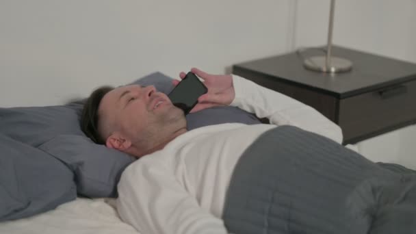 Hombre de mediana edad hablando en Smartphone mientras duerme en la cama
 - Imágenes, Vídeo