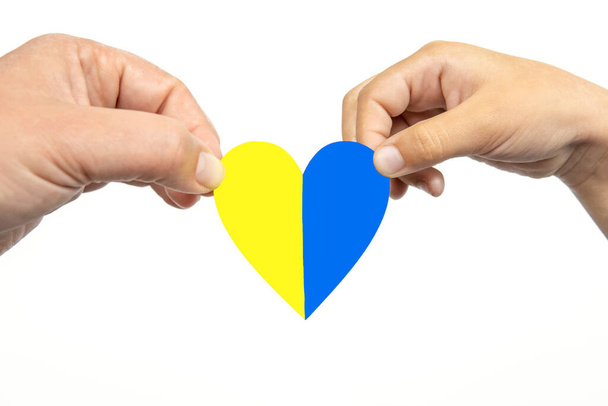Due mani che tengono il cuore con bandiera ucraina su sfondo bianco. Fermare la guerra Russia Ucraina. - Foto, immagini