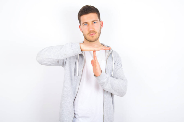 young caucasian man wearing casual clothes over white background feels tired and bored, making a timeout gesture, needs to stop because of work stress, time concept. - Photo, Image