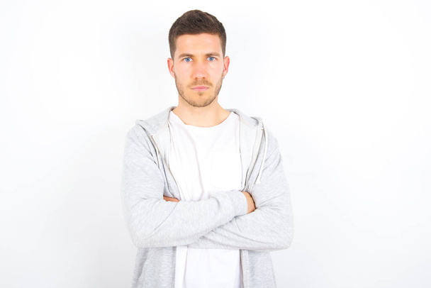 Picture of angry young caucasian man wearing casual clothes over white background looking camera. - Photo, Image