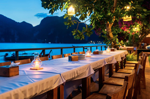 Обеденный стол с видом на пляж Пхи Пхи на рассвете после захода солнца, Краби, Таиланд. Отдыхающий или летний отдых в тропической стране, Сиам. - Фото, изображение