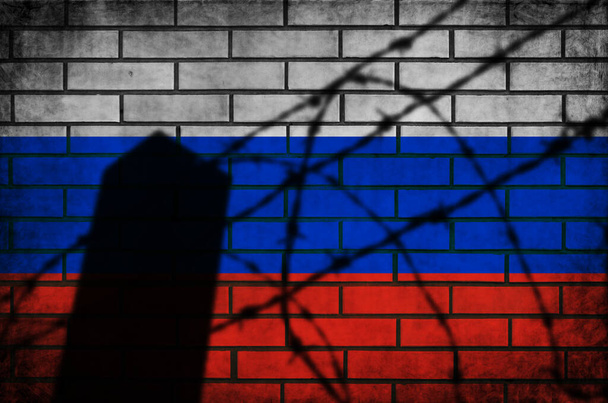 Russische vlag met prikkeldraad. Conflict en oorlogsconcept. Grunge achtergrond textuur op baksteen muur foto - Foto, afbeelding
