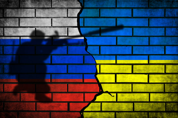 Rusland vs Oekraïne conflict en oorlog vlaggen achtergrond. Militair bewapende mannen silhouet op bakstenen muur - Foto, afbeelding