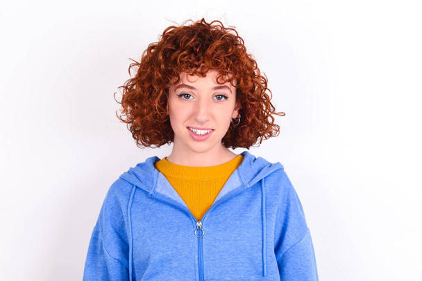 giovane ragazza rossa indossa giacca blu su sfondo bianco con un bel sorriso raggiante espressione compiaciuta. Concetto di emozioni positive - Foto, immagini