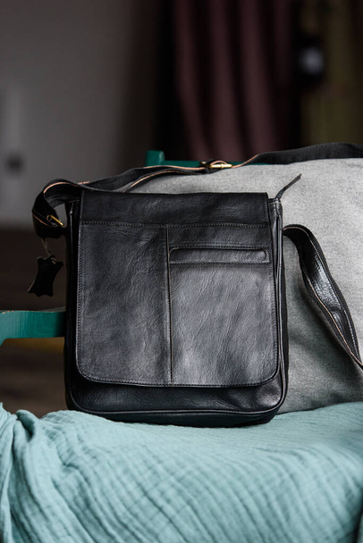 крупным планом фото черной кожаной сумки мессенджера на стуле - Фото, изображение