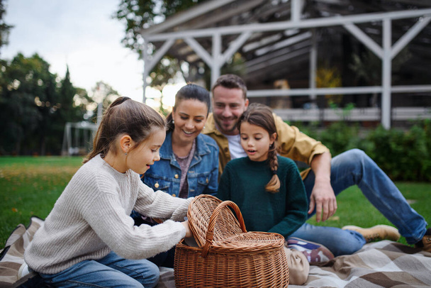 幸せな若い家族が毛布の上に座って、レストランエリアで屋外でピクニックをしています. - 写真・画像