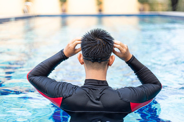 Sportovní a rekreační koncept mužské mládeže, která začíná plavat v modrém bazénu. - Fotografie, Obrázek