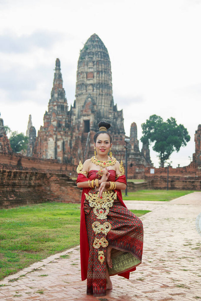 Asie femme portant une robe traditionnelle thaïlandaise, elle est en poste avec un ancien fond de temple en ruine. - Photo, image