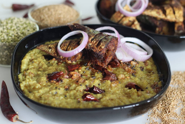 こども雑穀を使った鍋料理の一つ。インドでは、こどうキビKhichdiとして知られています。揚げサバ魚とタマネギのリングを添えて。白地に撃たれた. - 写真・画像