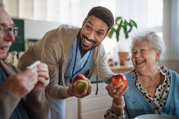 Caregiver bringing healthy snack to senior woman and man in nursing home care center. - Photo, Image