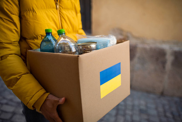 Close up of volunteer cyrrying box with Humanitarian aid for Ukrainian refugees in street - Foto, Bild