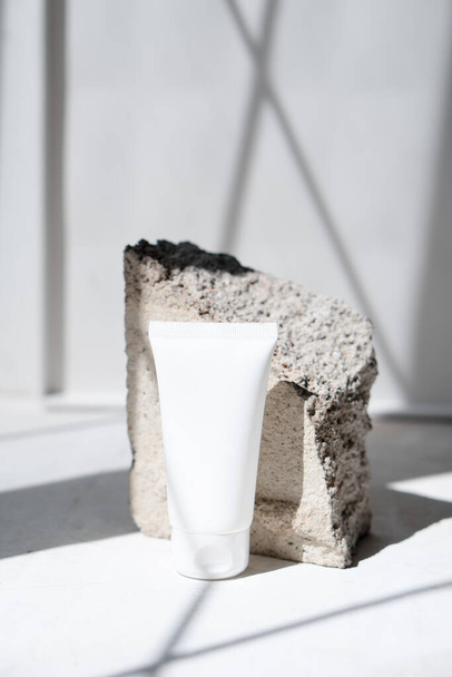 Tubo de crema blanca limpia con sombras de moda y textura de piedra - Foto, imagen