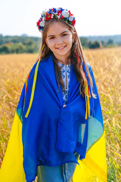Κοριτσάκι με σημαία Ουκρανίας φορώντας στεφάνι από λουλούδια - Φωτογραφία, εικόνα