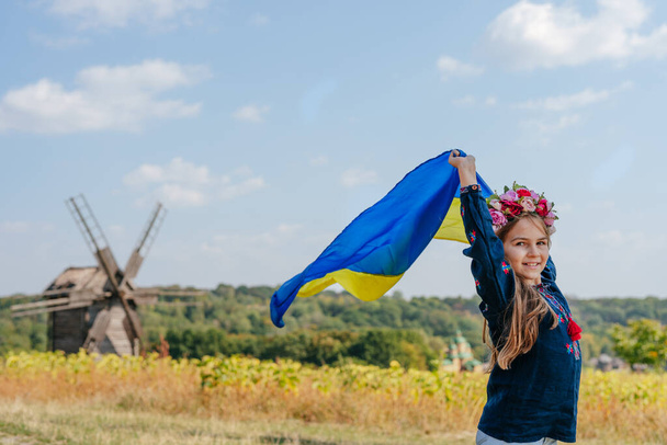 Κορίτσι που φοράει εθνικά ρούχα και στεφάνι κρατώντας σημαία της Ουκρανίας - Φωτογραφία, εικόνα
