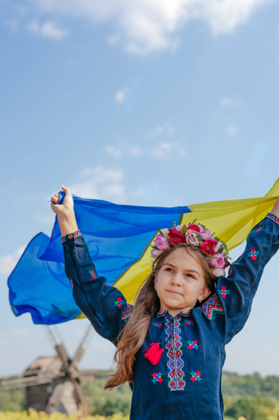 Girl wearing national clothes and wreath holding flag of Ukraine - Fotografie, Obrázek
