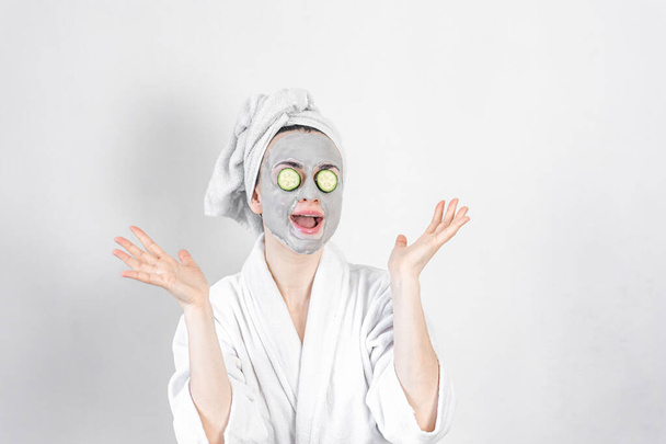 Μια νεαρή γυναίκα με μια πήλινη μάσκα στο πρόσωπό της. - Φωτογραφία, εικόνα