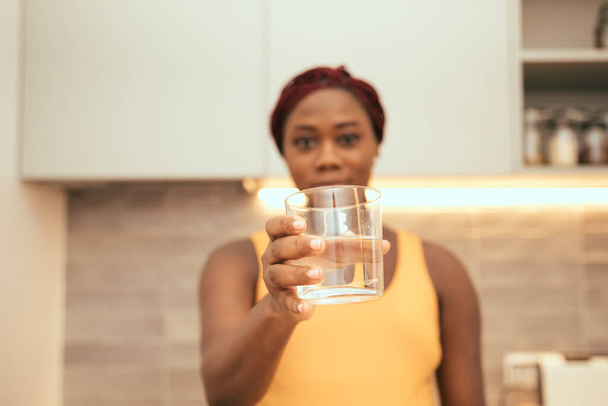 μαύρη γυναίκα δείχνει ένα ποτήρι γεμάτο νερό - Φωτογραφία, εικόνα