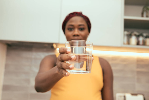 Schwarze Frau zeigt ein Glas voll Wasser - Foto, Bild
