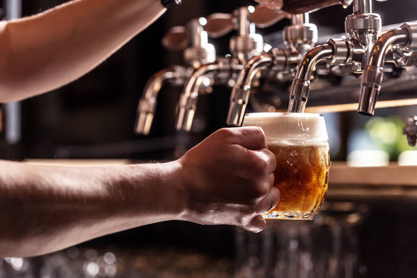 Woman hands of the pub employee tapping beer into a rounded mug. - Foto, Bild