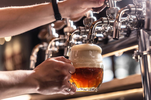 Tapping a half dark and half light beer into a mug by a bartender. - Valokuva, kuva